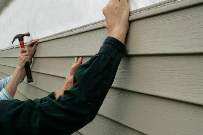 Contractor installing siding panel by hand