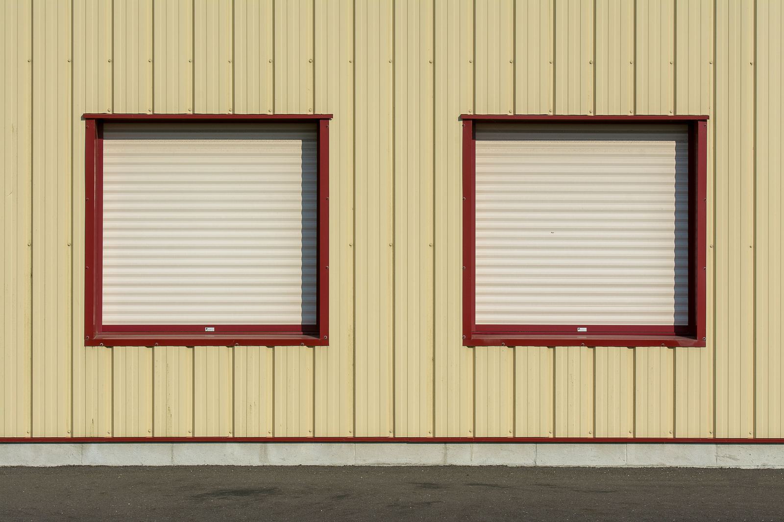 Yellow corrugated metal commercial building with red-framed windows