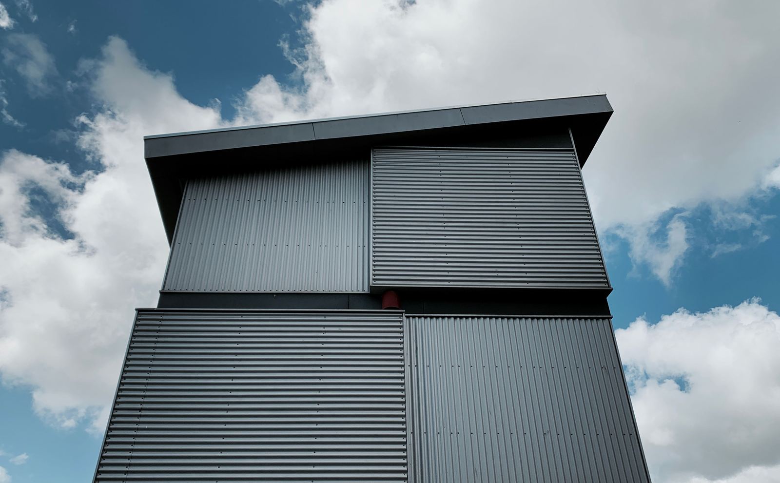 Modern gray corrugated metal building against a blue sky