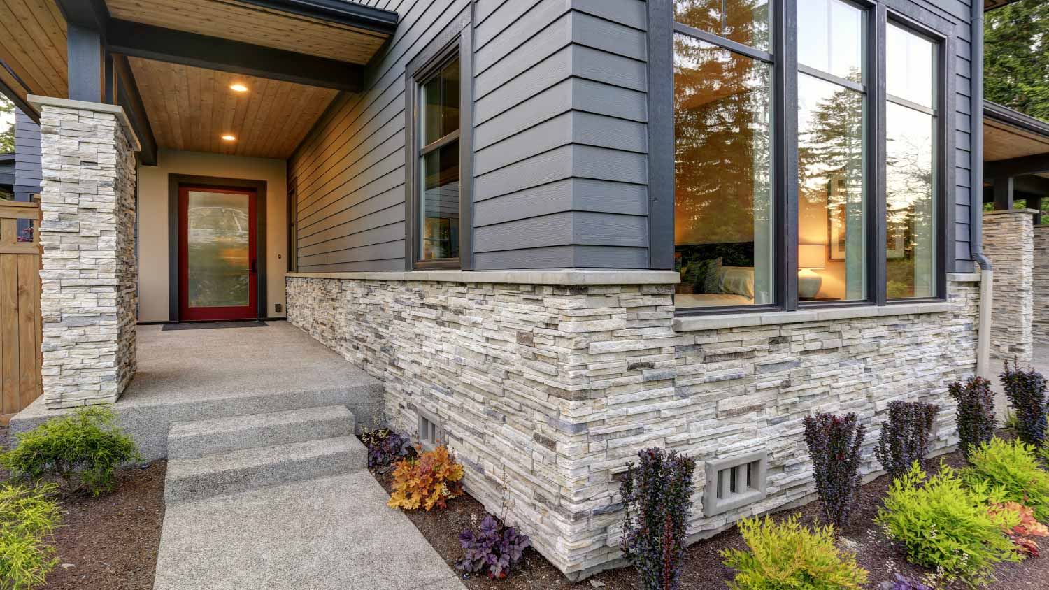 Modern home with stacked stone veneer base and red front door
