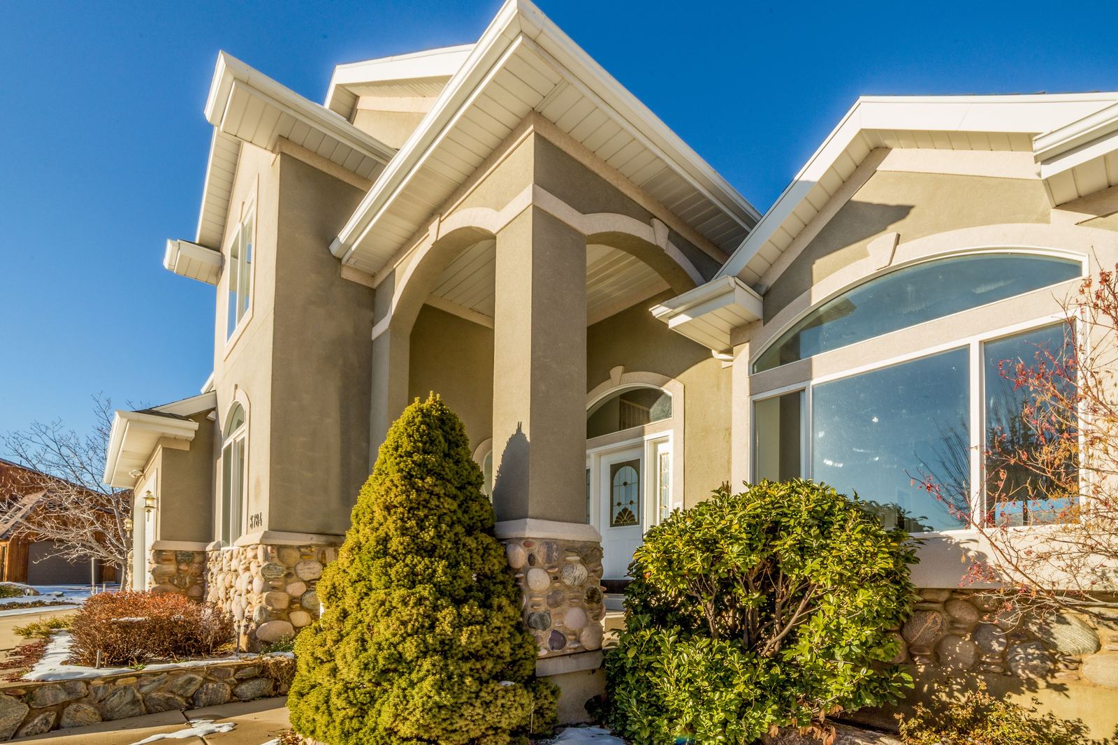 Tan stucco home exterior with arched entry and stone accents