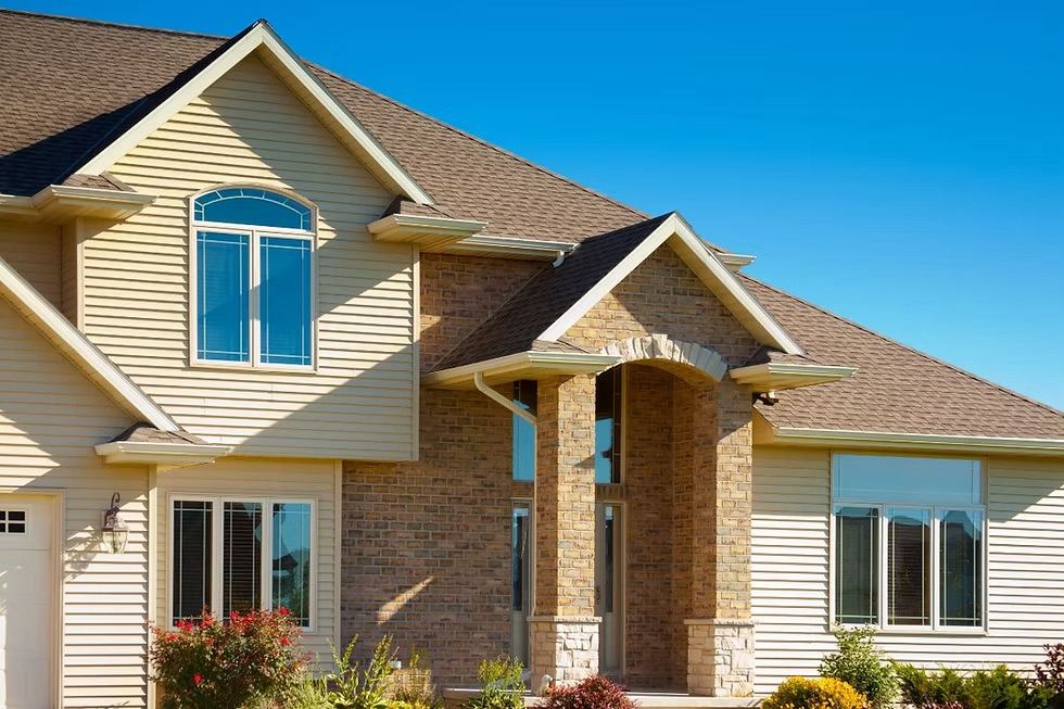 Cream vinyl siding home with a stone entry accent